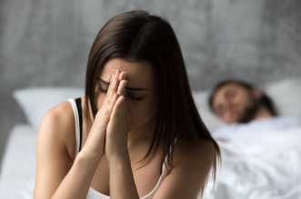 体に自信がなく不安を感じている女性と距離のあるパートナー