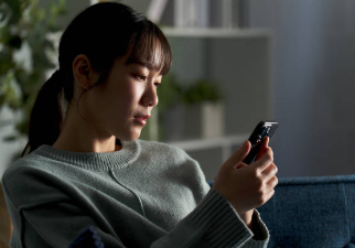 女風の利用を迷いながらスマホを見ている女性