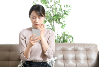 女風の利用を考えながら不安そうにスマホを見る女性