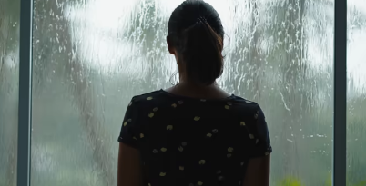 雨の窓を見ながら体と心の関係を考える女性