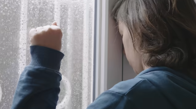 雨の窓を見ながら体と心の関係を考える女性