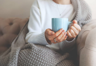 ソファでマグカップを持ちリラックスする女性